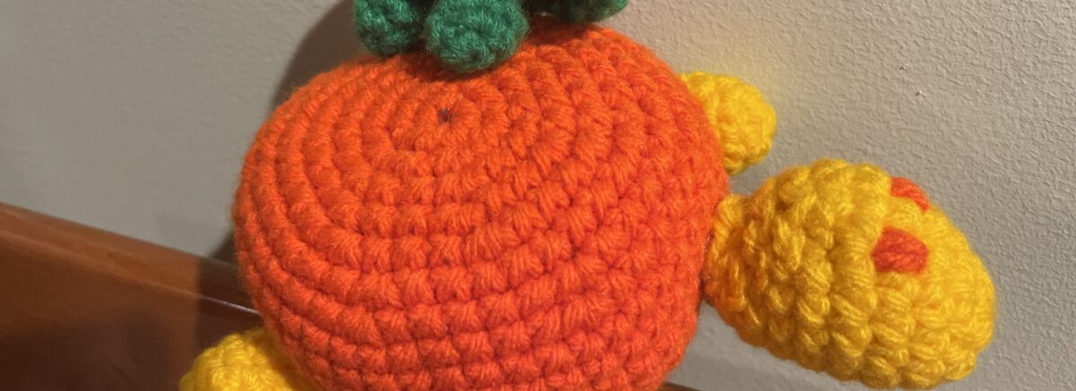 A tiny toy turtle perched on the bag of a larger toy turtle