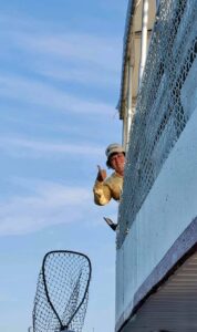 Jeanine Spencer giving a thumbs-up over the rail of the fishing boat