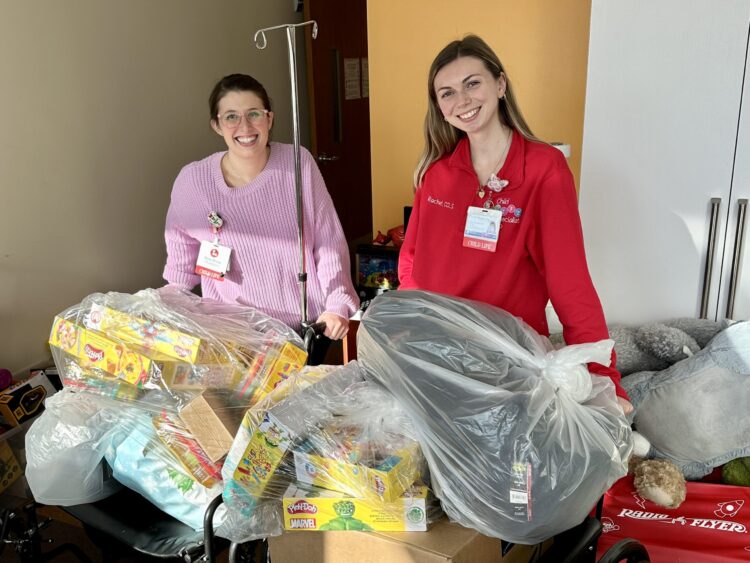 Two Child Life staffers at Stony Brook Children's Hospital with wagons full of clothes and toys