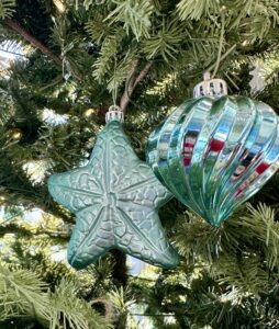Beautiful blue glass ornaments on a Christmas tree, one shaped like a starfish, the other like a heart