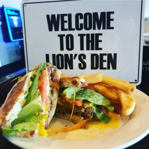 Sandwich and fries with Welcome to the Lion's Den sign