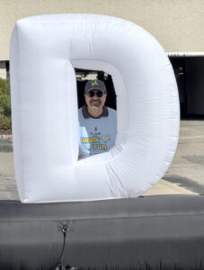 Dave poses behind the letter D