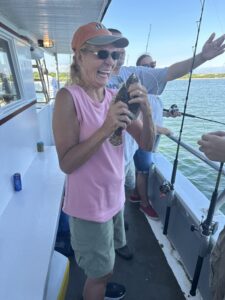 Laughing angler holding fish still on line